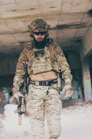 A bearded soldier in a special forces uniform walks through an abandoned building after a successful...