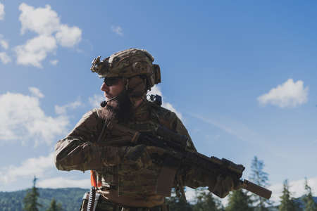 War concept. A bearded soldier in a special forces uniform fighting an enemy in a forest area. Selective focusの写真素材