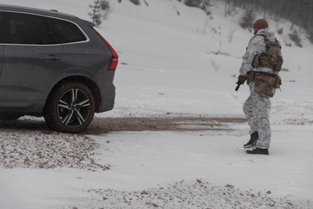 Soldier in winter camouflaged uniform in Modern warfare army on a snow day on forest battlefield...