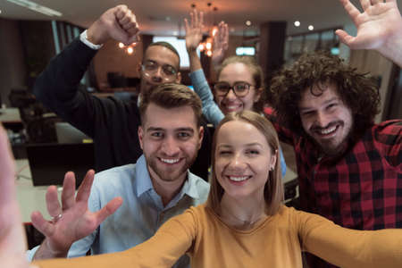 Group of business people during break from the work taking selfie picture while enjoying free time in relaxation area at modern open plan startup office. Selective focusの写真素材