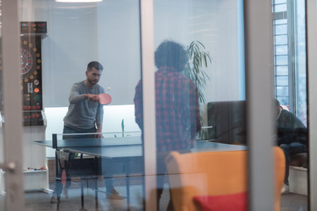 Two young start up business man playing  table tennis   tennis at modern creative office space...
