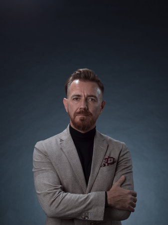 Portrait of a stylish elegant senior businessman with a beard and casual business clothes in photo studio isolated on dark background gesturing with handsの写真素材