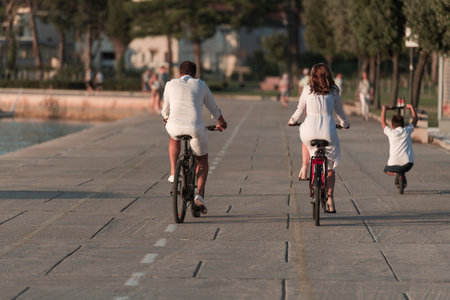 Happy family enjoying a beautiful morning by the sea together, parents riding a bike and their son...