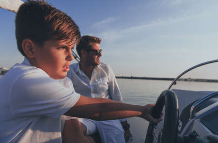 Father and son enjoy their vacation together while riding a luxury boat at sea. Selective focusの写真素材