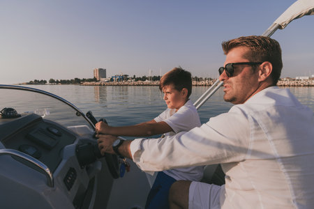 Father and son enjoy their vacation together while riding a luxury boat at sea. Selective focusの写真素材