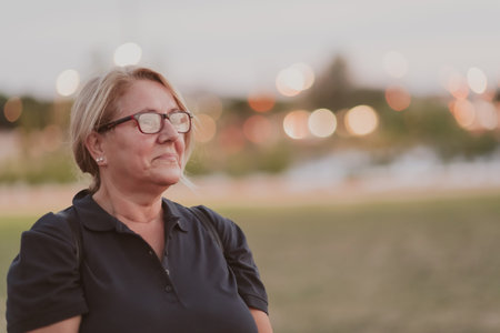 Portrait of an elderly woman with blonde hair and glasses on the beaches of the Mediterranean Sea at sunset. Selective focusの写真素材