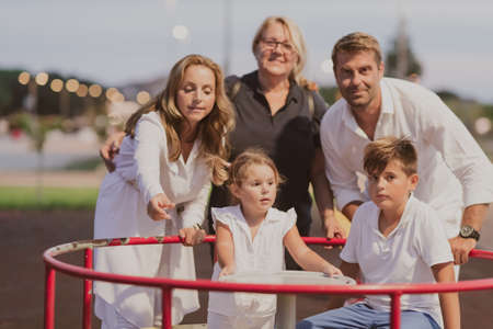 An elderly couple in casual clothes with their children and grandmother spend time together in the park on vacation. Family time. Selective focusの写真素材