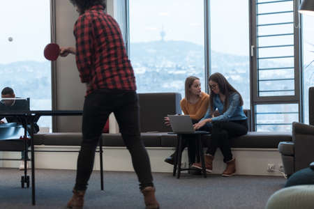 Two business women sitingt in a modern coworking space on a break from work and relax using a laptop. Selective focusの写真素材