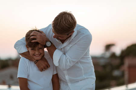 Father and son spend time together on the roof of the house while enjoying the sunset. Selective focusの写真素材
