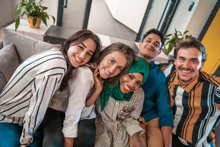Group of business people during break from the work taking selfie picture while enjoying free time in relaxation area at modern open plan startup office. Selective focusの写真素材