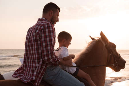 Father and son enjoy riding horses together by the sea. Selective focusの写真素材
