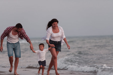 The family enjoys their vacation as they walk the sandy beach with their son. Selective focusの写真素材