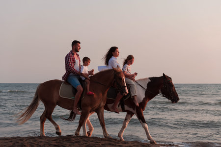 The family spends time with their children while riding horses together on a sandy beach. Selective...