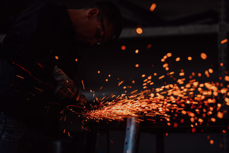 Heavy Industry Engineering Factory Interior with Industrial Worker Using Angle Grinder and Cutting a...