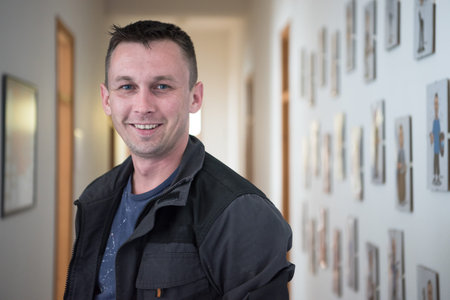 a portrait of a man in a work suit standing in the hallway of a factory