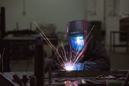 Professional Heavy Industry Welder Working Inside factory, Wears Helmet and Starts Welding....
