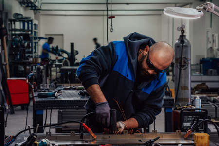 Industrial worker man soldering cables of manufacturing equipment in a factory. Selective focusの写真素材