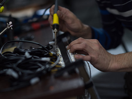 Industrial worker man soldering cables of manufacturing equipment in a factory. Selective focus