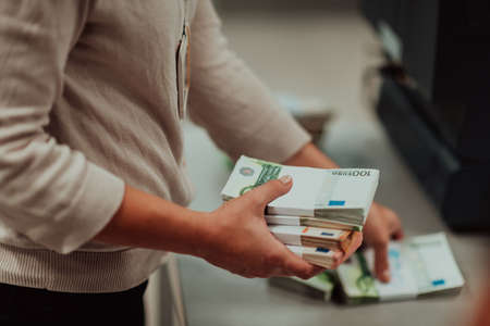 Bank employees holding a pile of paper banknotes while sorting and counting inside bank vault. Large amounts of money in the bankの写真素材