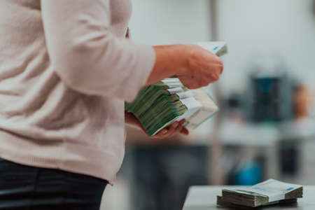 Bank employees holding a pile of paper banknotes while sorting and counting inside bank vault. Large amounts of money in the bankの写真素材