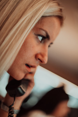 Female security guard operator talking on the phone while working at workstation with multiple displays Security guards working on multiple monitorsの写真素材