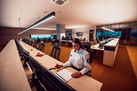 Group of Security data center operators working in a CCTV monitoring room looking on multiple...