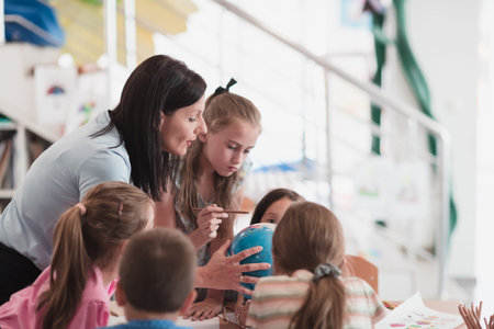 Female teacher with kids in geography class looking at globe. Side view of group of diverse happy...