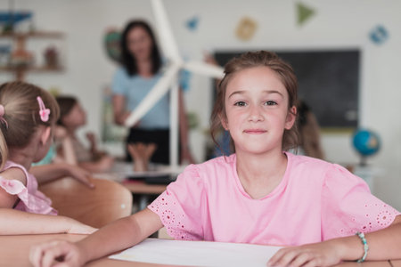 Little girls sitting in elementary school drawing on paper with their friends while sitting in a...