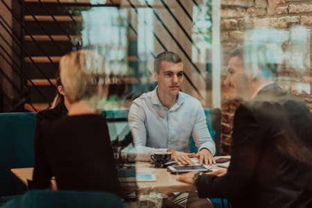 Happy businesspeople smiling cheerfully during a meeting in a coffee shop. Group of successful business professionals working as a team in a multicultural workplace.の写真素材