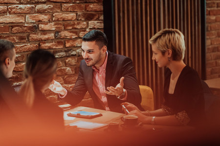 Happy businesspeople smiling cheerfully during a meeting in a coffee shop. Group of successful...