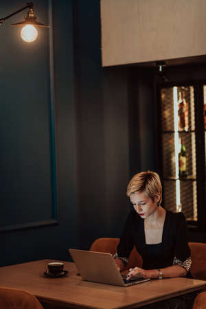 Businesswoman sitting in a cafe while focused on working on a laptop and participating in an online meetings. Selective focus. High quality photoの写真素材