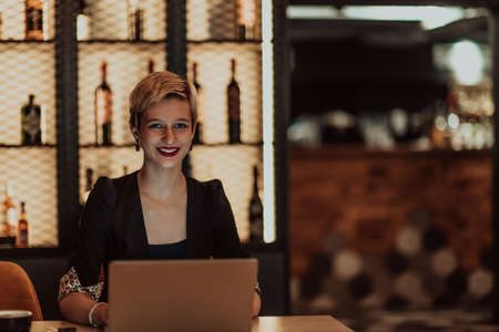Businesswoman sitting in a cafe while focused on working on a laptop and participating in an online meetings. Selective focus. High quality photoの写真素材