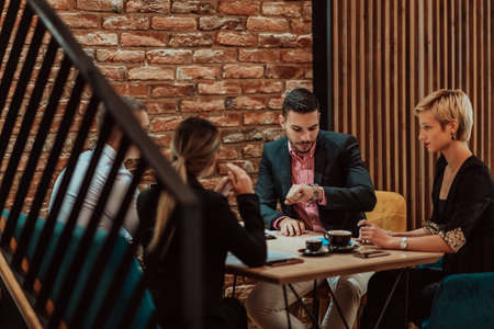 Happy businesspeople smiling cheerfully during a meeting in a coffee shop. Group of successful business professionals working as a team in a multicultural workplace.の写真素材
