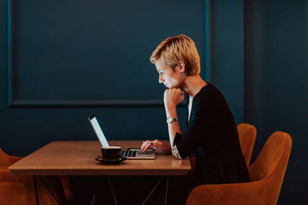 Businesswoman sitting in a cafe while focused on working on a laptop and participating in an online meetings. Selective focus. High quality photoの写真素材