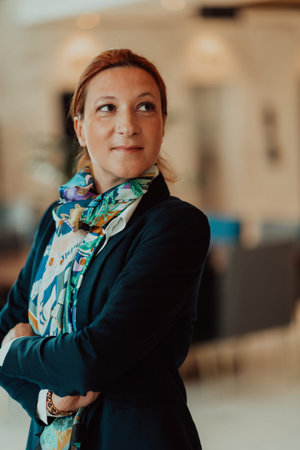 Portrait of business senior woman with crossed arms standing in modern corporation. Selective focus