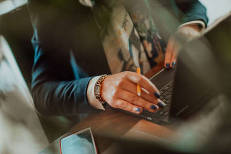 Close-up photo of a woman using a laptop to do business projects and tasks while sitting in a modern corporationの写真素材