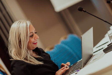 Photo of an elderly woman using a laptop to carry out business projects and tasks while sitting in a modern corporationの写真素材