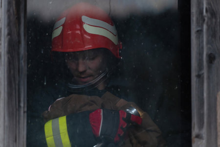 Firefighter hero carrying baby girl out from burning building area from fire incident. Rescue people from dangerous placeの写真素材
