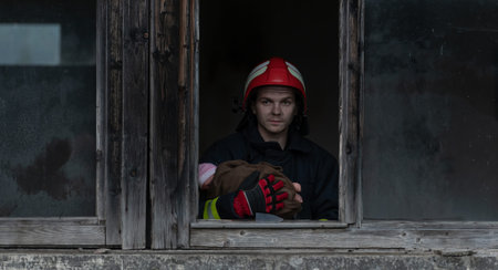 Firefighter hero carrying baby girl out from burning building area from fire incident. Rescue people...