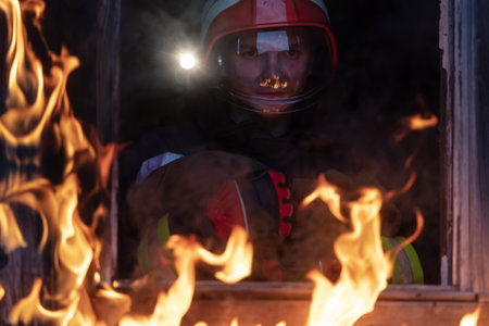 Firefighter hero carrying baby girl out from burning building area from fire incident. Rescue people from dangerous placeの写真素材