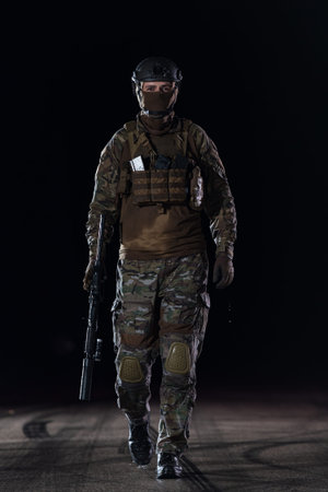 Army soldier in Combat Uniforms with an assault rifle, plate carrier and combat helmet going on a...