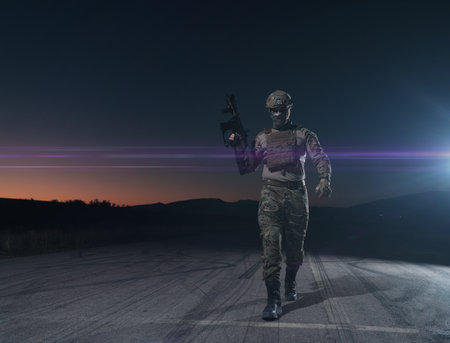 Army soldier in Combat Uniforms with an assault rifle, plate carrier and combat helmet going on a dangerous mission on a rainy night.の写真素材