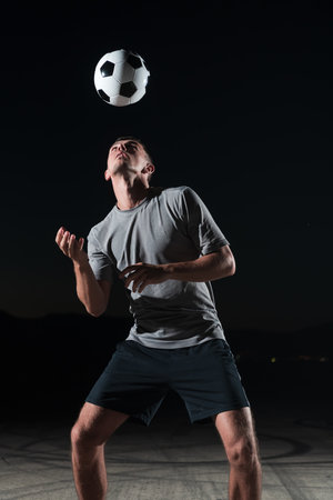 portrait of a young handsome soccer player man on a street playing with a football ball.の写真素材
