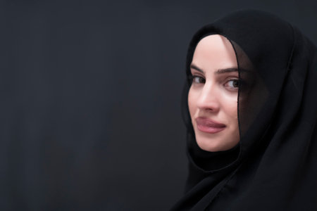 Portrait of beautiful muslim woman in fashionable dress with hijab in front of black chalkboard representing modern islam fashion and ramadan kareem conceptの写真素材