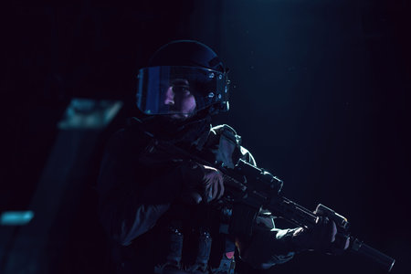 Army soldier in Combat Uniforms with an assault rifle and combat helmet night mission dark...