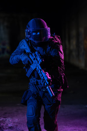 Army soldier in Combat Uniforms with an assault rifle and combat helmet night mission dark...