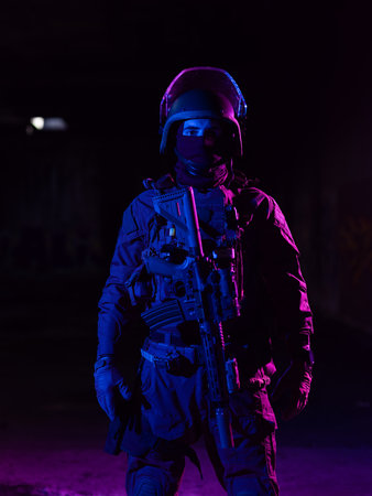 Army soldier in Combat Uniforms with an assault rifle and combat helmet night mission dark background. Blue and purple gel light effect.の写真素材