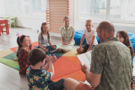 Reading time in elementary school or kindergarten, teacher reading a book to kids in elementary school or kindergaden. Selective focusの写真素材
