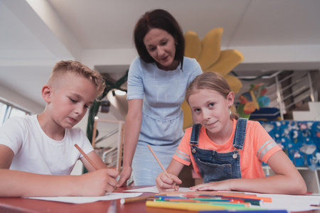 Creative kids during an art class in a daycare center or elementary school classroom drawing with...