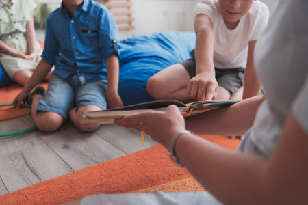 Reading time in an elementary school or kindergarten, a teacher reads a book to children in an elementary school or kindergarten. The concept of pre-school education. Selective focusの写真素材